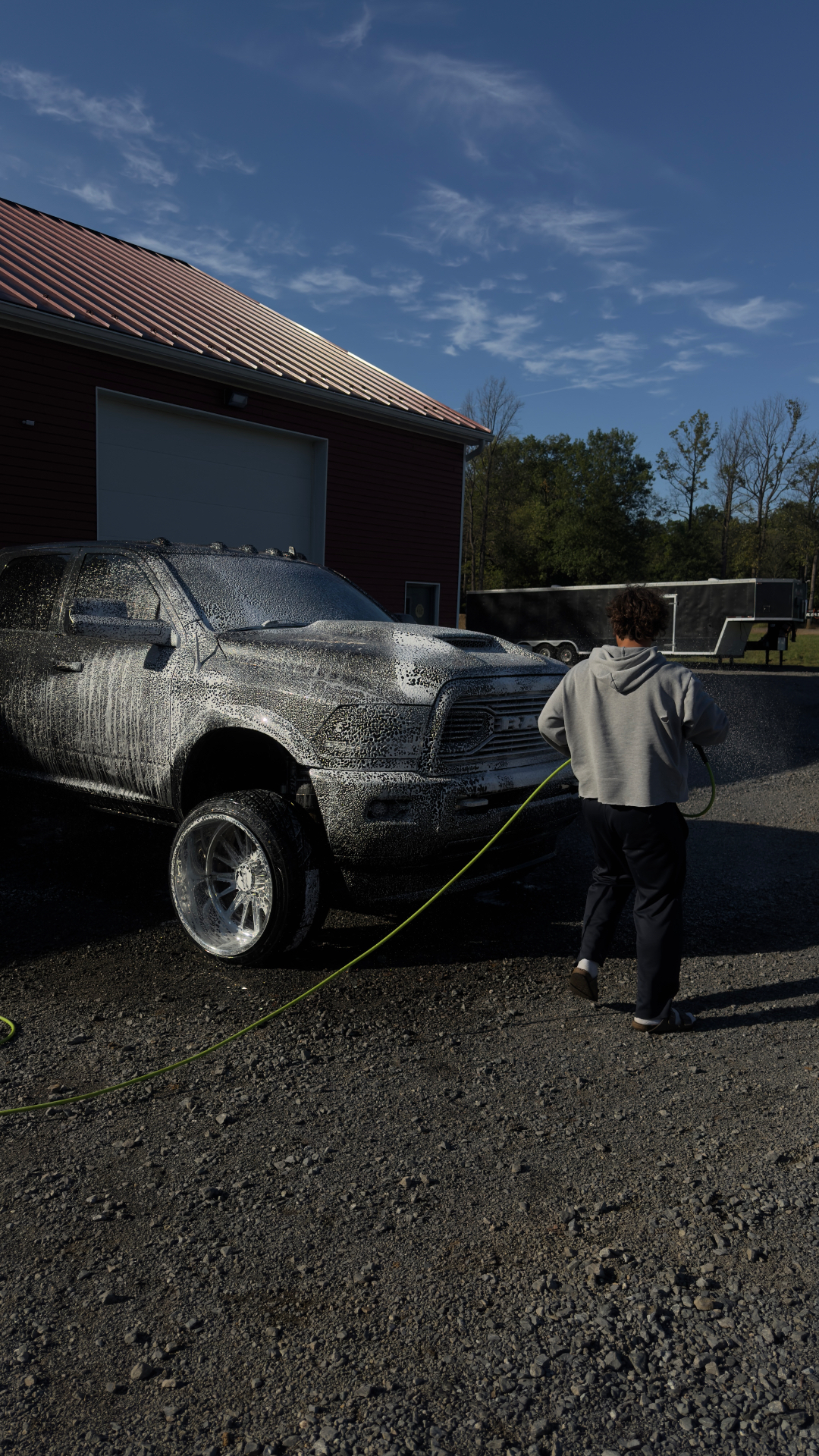 Diesel truck covered in foam being rinsed with a lime green hose